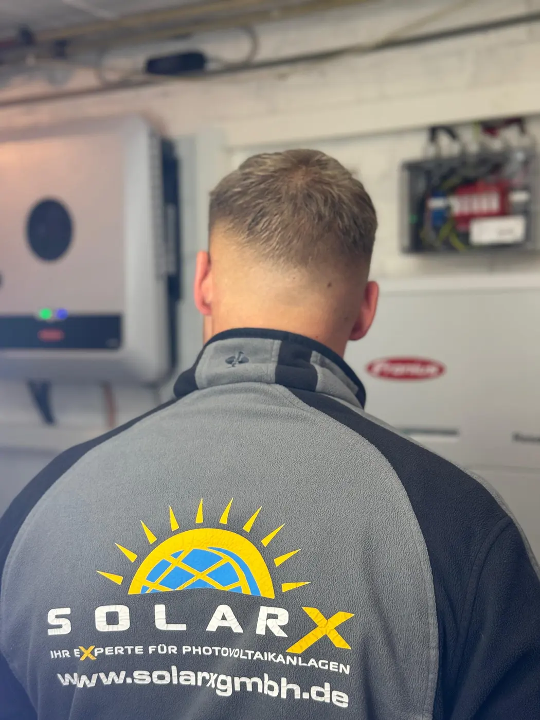 SolarX Monteur bei der Inbetriebnahme einer Photovoltaikanlage SolarX-Monteur bei der Arbeit an einer Fronius-Anlage