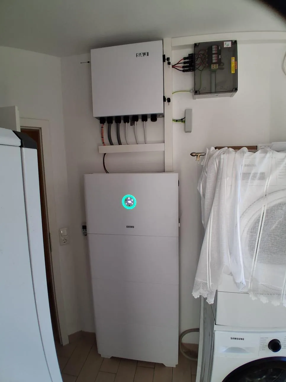 Photovoltaik-Referenz SolarX – Speicher und Wechselrichter neben der Waschmaschine SolarX Referenz: Speicher und Wechselrichter in einem Hauswirtschaftsraum neben der Waschmaschine