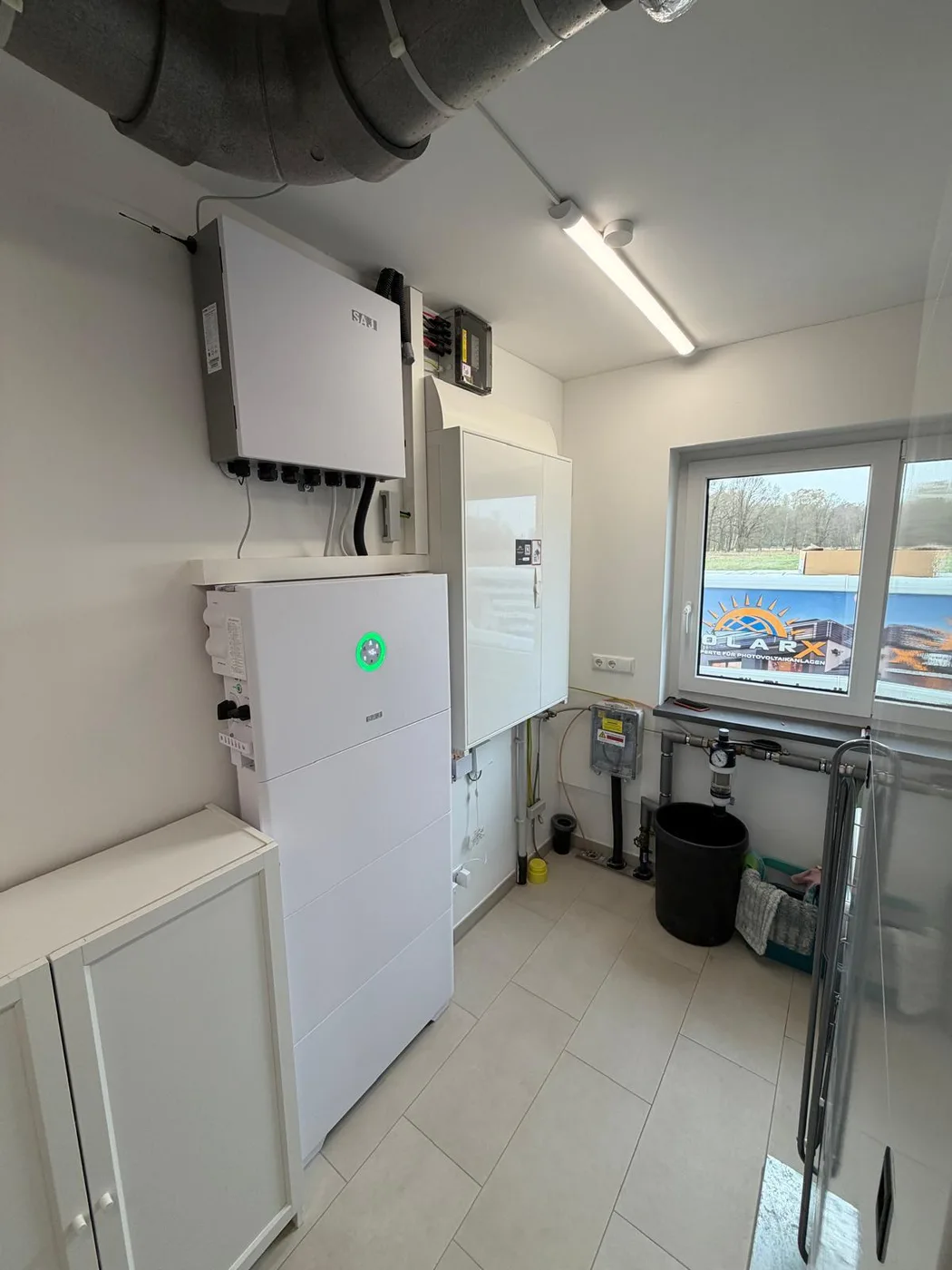 Photovoltaik-Referenz SolarX – Technikraum mit Speicher und Wechselrichter SolarX Referenz: Technikraum mit Fenster und Lüftungsrohr, darin Speicher und Wechselrichter