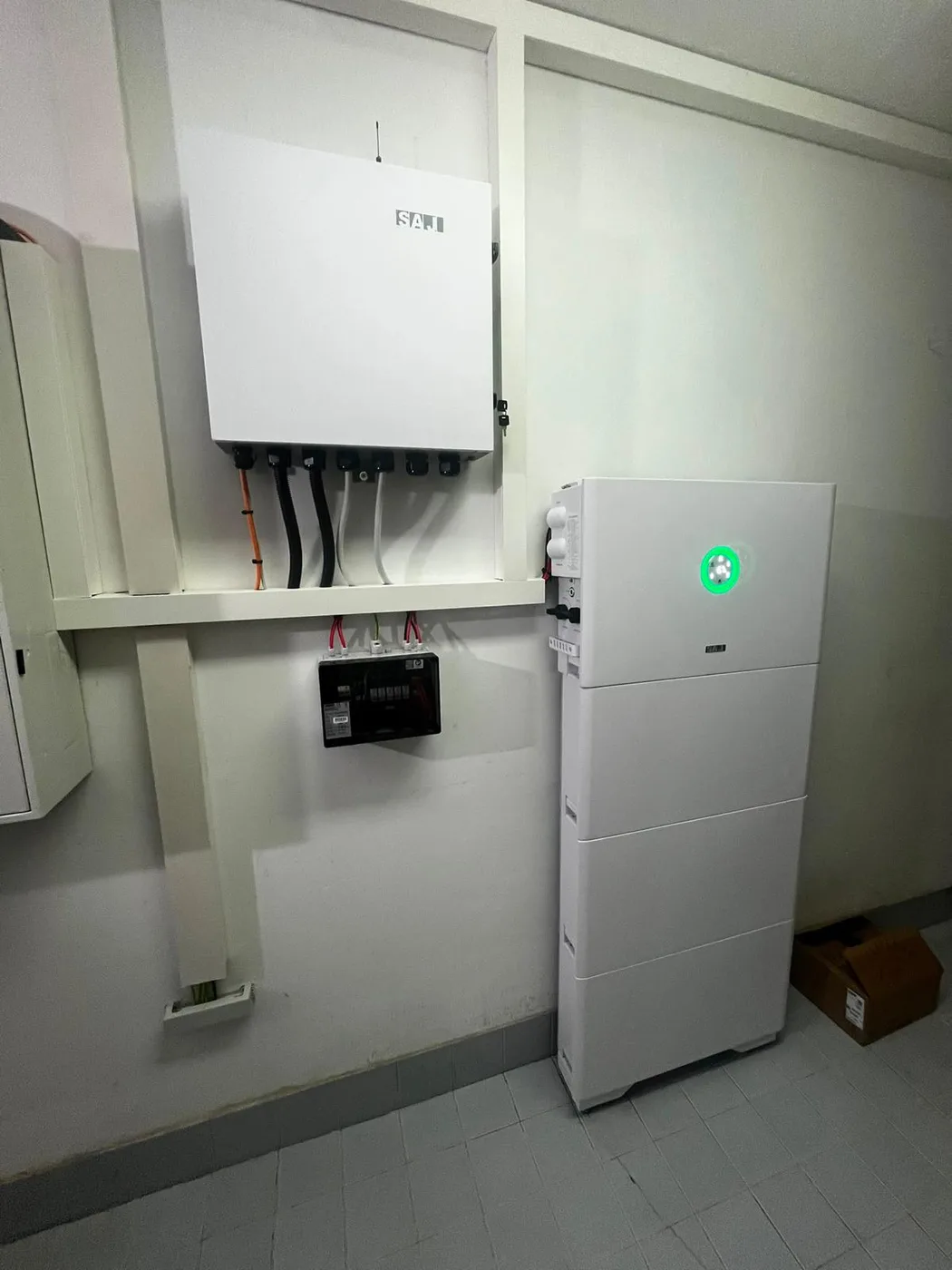 Photovoltaik-Referenz SolarX – Wechselrichter mit Trennschalter und Speicher SolarX Referenz: Wandmontierter Wechselrichter mit Trennschalter, darunter der Speicher mit grünem Statusring